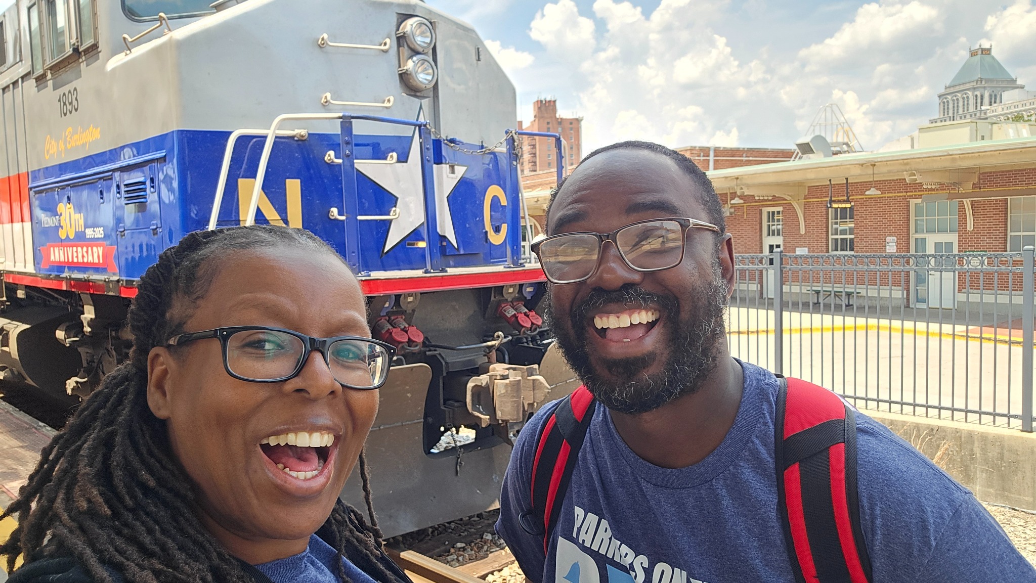 Charvon and Brandon Parker smiling beside a North Carolina train